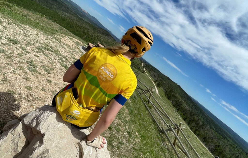 A young woman in a Union City Fondo jersey looks out over the expansive Montana landscape.